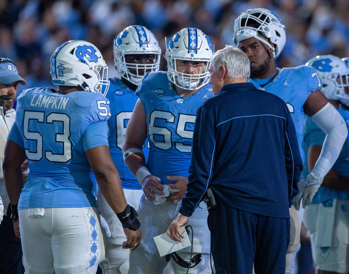 North Carolina coach Mack Brown talks offensive lineman Willie Lampkin (53) and center Corey Gaynor (65) during a time out in the second quarter against Virginia on Saturday, October 21, 2023 at Kenan Stadium in Chapel Hill, N.C.
