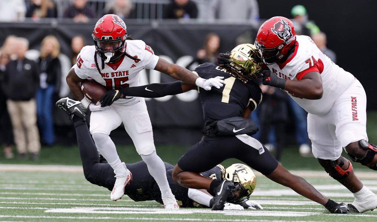 N.C. State wide receiver Keyon Lesane (15) looks to escape from Wake Forest defensive back Caelen Carson (1) as N.C. State offensive lineman Anthony Belton (74) blocks during the first half of N.C. State’s game against Wake Forest at Allegacy Stadium in Winston-Salem, N.C., Saturday, Nov. 11, 2023.