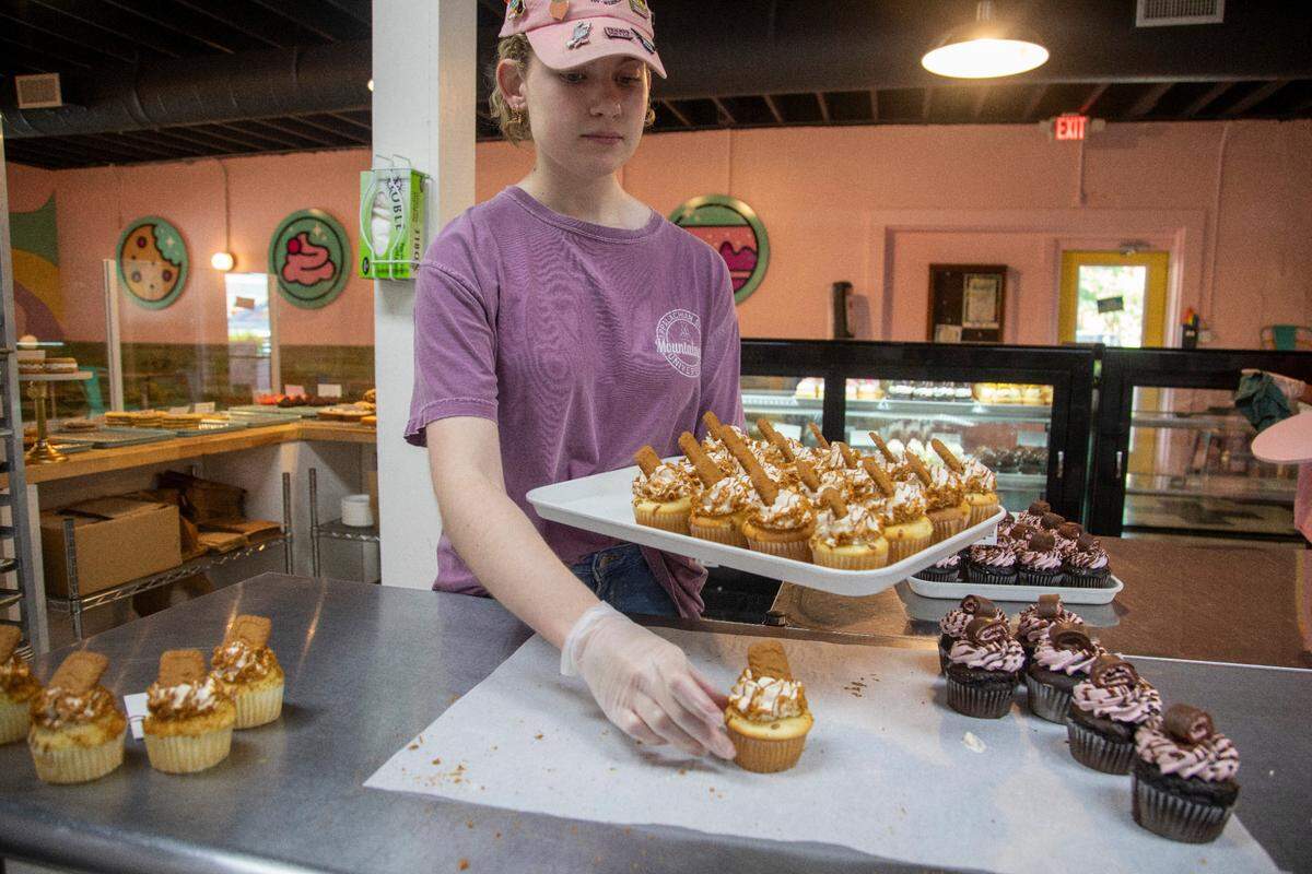 Mackenzie Lewis prepares to put cupcakes in a display case for sale at Treat Yo’ Self bakery in Wilson. Owner Greg Mason has more than 1 million TikTok followers and he and his husband Alex Mason started Wilson Pride.