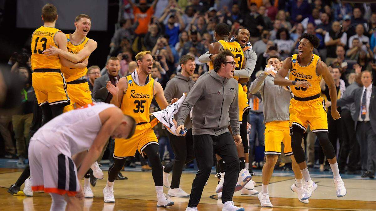 Virginia guard Kyle Guy, left, is bent over in disappointment as UMBC players and team officials celebrate their upset of the tournament's top seed in the first round of the NCAA tournament in March. It was the first time a No. 1 seed has been defeated by a No. 16 seed in tournament history.