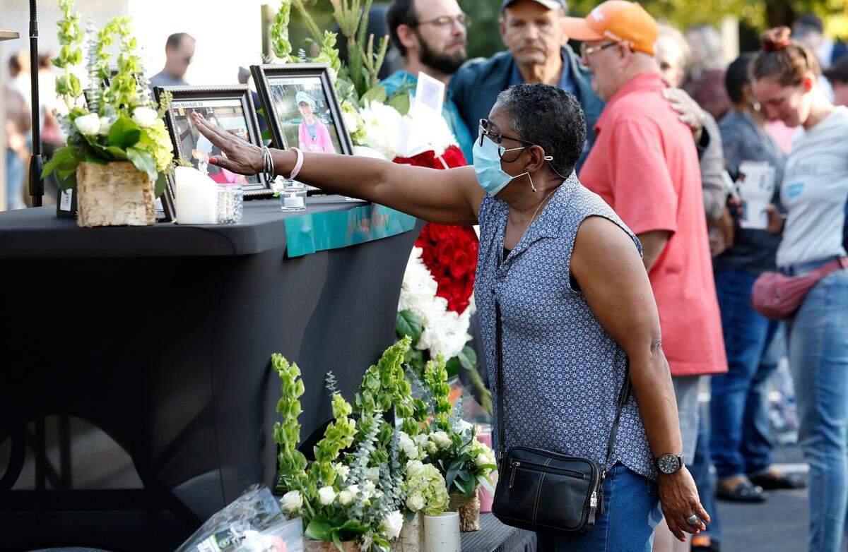 After a candlelight vigil outside the Hedingham clubhouse Saturday, Oct. 15, 2022, attendees look at a memorial for those killed and wounded in a mass shooting in the Hedingham neighborhood in Raleigh, N.C., on Thursday.