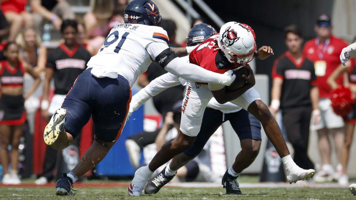 N.C. State quarterback CJ Bailey (11) tries to escape from Virginia defensive tackle Jason Hammond (91) during the first half of N.C. State’s game against Virginia at Carter-Finley Stadium in Raleigh, N.C., Sat. Sept. 6, 2025.