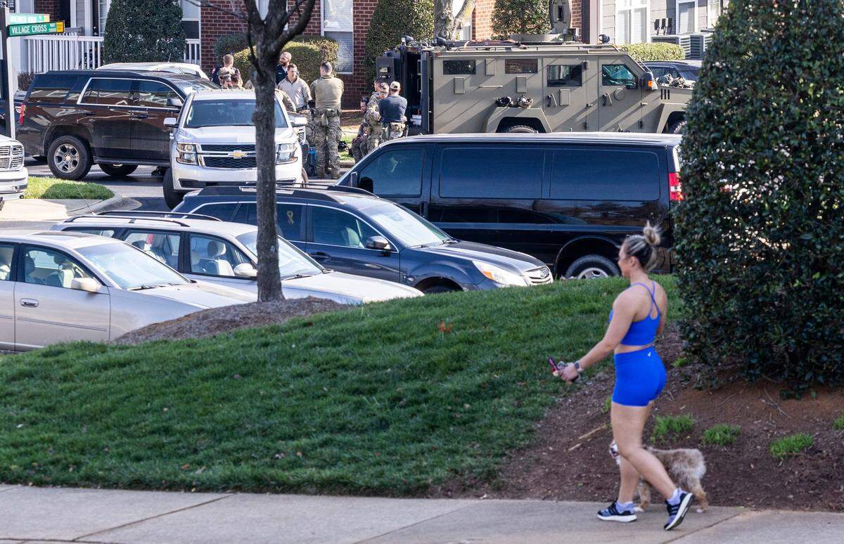 FBI agents and law enforcement officers work the scene of a standoff at Tryon Villages apartments as a person walks their dog Wednesday, Feb. 22, 2023.