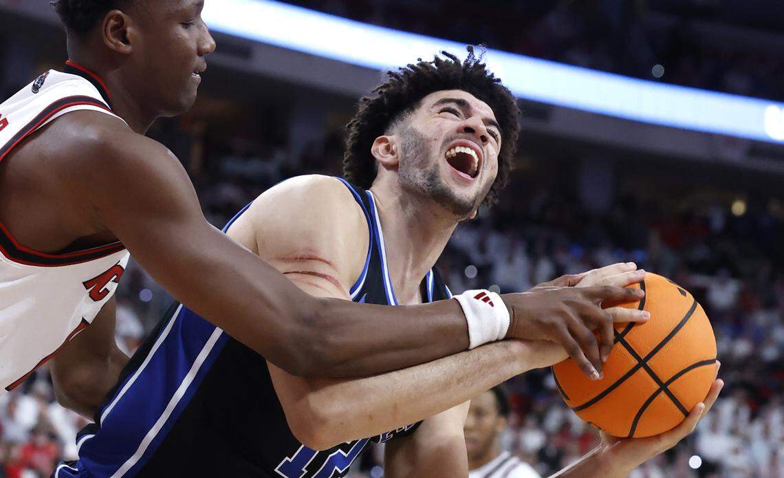 NC State's Musa Sagnia (13) fouls Duke’s Cameron Boozer (12) during the second half of Duke’s 93-64 victory over N.C. State at the Lenovo Center in Raleigh, N.C., Monday, March 2, 2026. Boozer has a deep scratch gotten in the game on his right arm