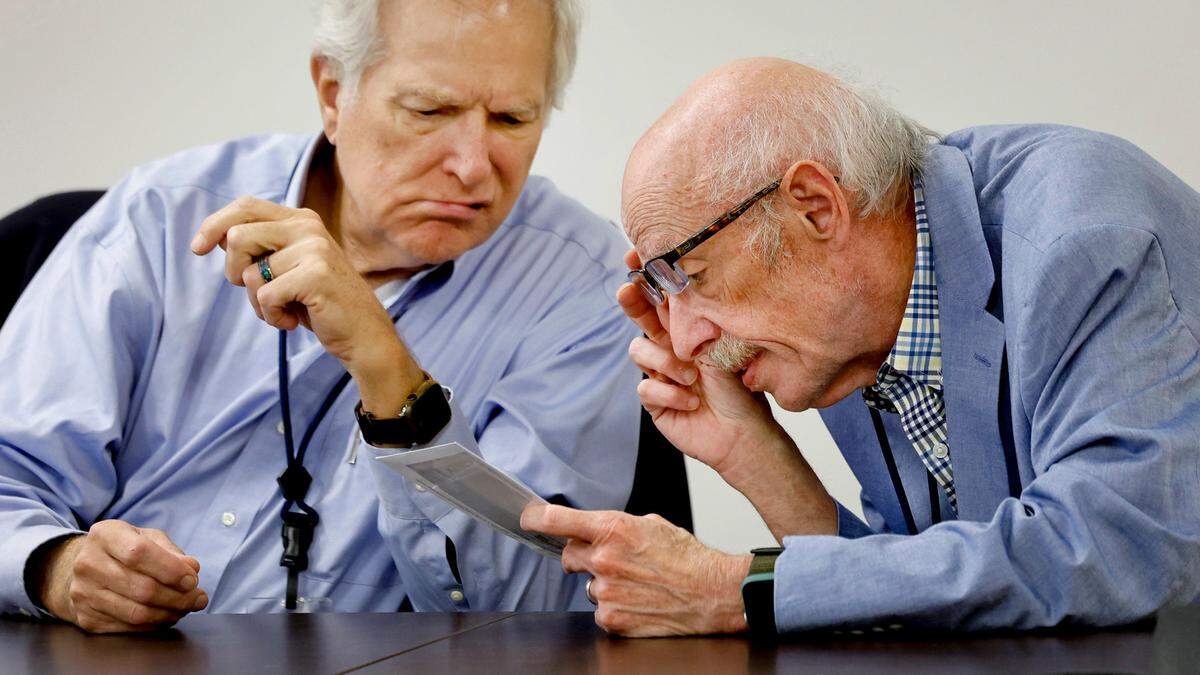 Wake County Board of Elections members Keith Weatherly, left, and Gerry Cohen inspect an absentee ballot during a board meeting at the Wake County Board of Elections Operations Center in Raleigh on Oct. 8, 2024.
