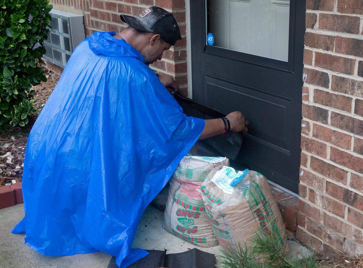 Patrick Bullard installs a flood bag in front of a doorway at the Camelot Village complex as Tropical Storm Debby soaks the Triangle with heavy rain on Thursday, Aug. 8, 2024, in Chapel Hill, N.C.