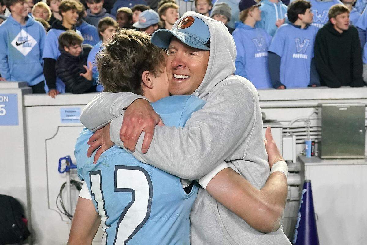 Watauga's Evan Burroughs (12) embraces his father Sean Burroughs, Watauga Baseball Coach, after their victory over Middle Creek in the NCHSAA 6A Football Championship  Game. The Middle Creek Mustangs and the Watauga Pioneers met in the NCHSAA 6A Football Championship game in Chapel Hill, N.C. on December 12, 2025. 