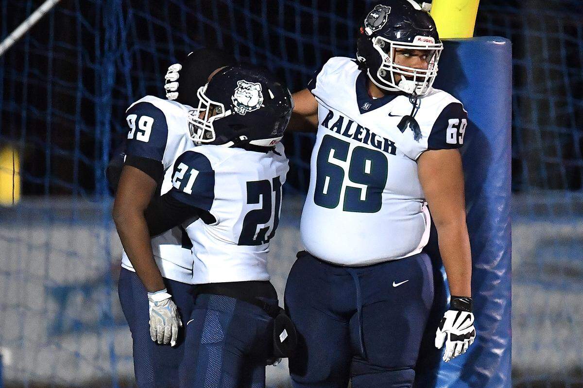 Southeast Raleigh's Jahkerion Price (21), Trevor Howard (69), and Jonathan Williams (99) react to their team's loss to Clayton in the NCHSAA7A playoff game. The Clayton Comets and the Southeast Raleigh Bulldogs met in the fourth round of the NCHSAA 7A Playoffs in Clayton, N.C. on November 28, 2025.