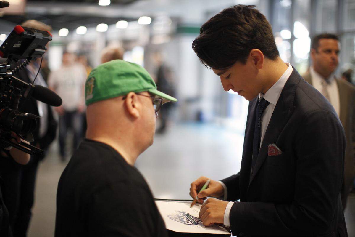 Carolina Hurricanes first round draft pick Ryan Suzuki, right, autographs a fan’s album during the second round of the NHL draft at Rogers Arena in Vancouver, British Columbia, Saturday, June 22, 2019. (Chad Hipolito/The Canadian Press via AP)