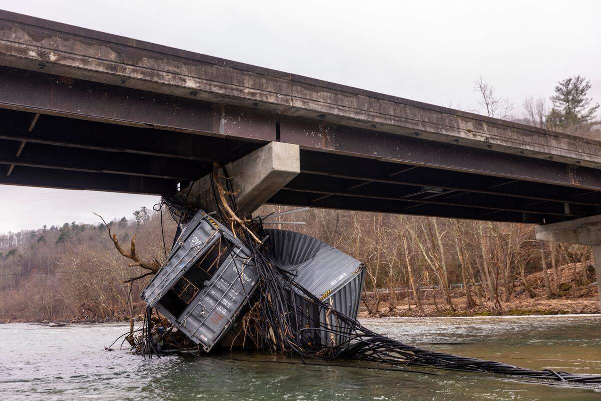 A crumpled shipping container and a tangle of plastic piping clings to a bridge support in the French Broad River near Marshall on Monday, Jan. 27, 2025. Using private donations, Mountain True launched a pilot program aimed at removing trash out of North Carolina rivers following catastrophic flooding from the remnants of Hurricane Helene last year.