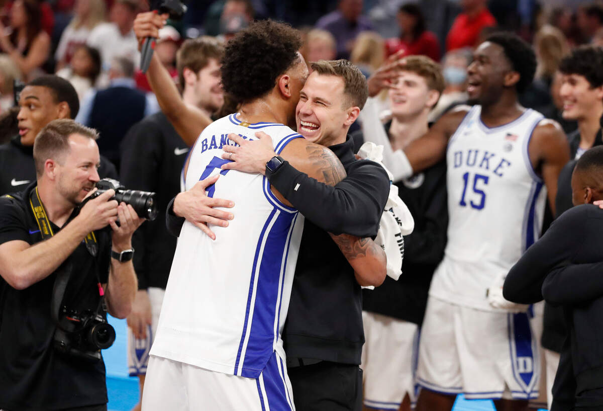 Duke’s Paolo Banchero (5) and associate head coach Jon Scheyer hug after Duke’s 78-69 victory over Arkansas in the NCAA Tournament West Regional finals at the Chase Center in San Francisco, Calif., Saturday, March 26, 2022.