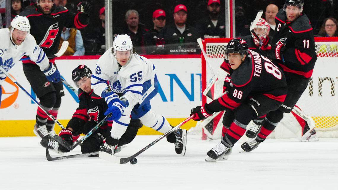 Mar 24, 2024; Raleigh, North Carolina, USA; Carolina Hurricanes defenseman Brett Pesce (22) and left wing Teuvo Teravainen (86) battle Toronto Maple Leafs left wing Tyler Bertuzzi (59) for the puck during the first period at PNC Arena. Mandatory Credit: James Guillory-USA TODAY Sports