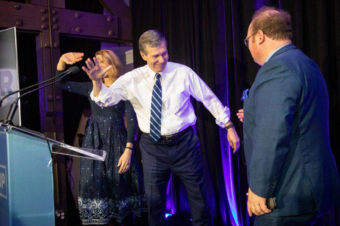 Gov. Roy Cooper prepares to shake hands with Wayne Goodwin, chair of the North Carolina Democratic Party, as he and his wife Kristin Cooper take the stage during a North Carolina Democratic Party primary election watch party at Traine Raleigh Tuesday, March 3, 2020.