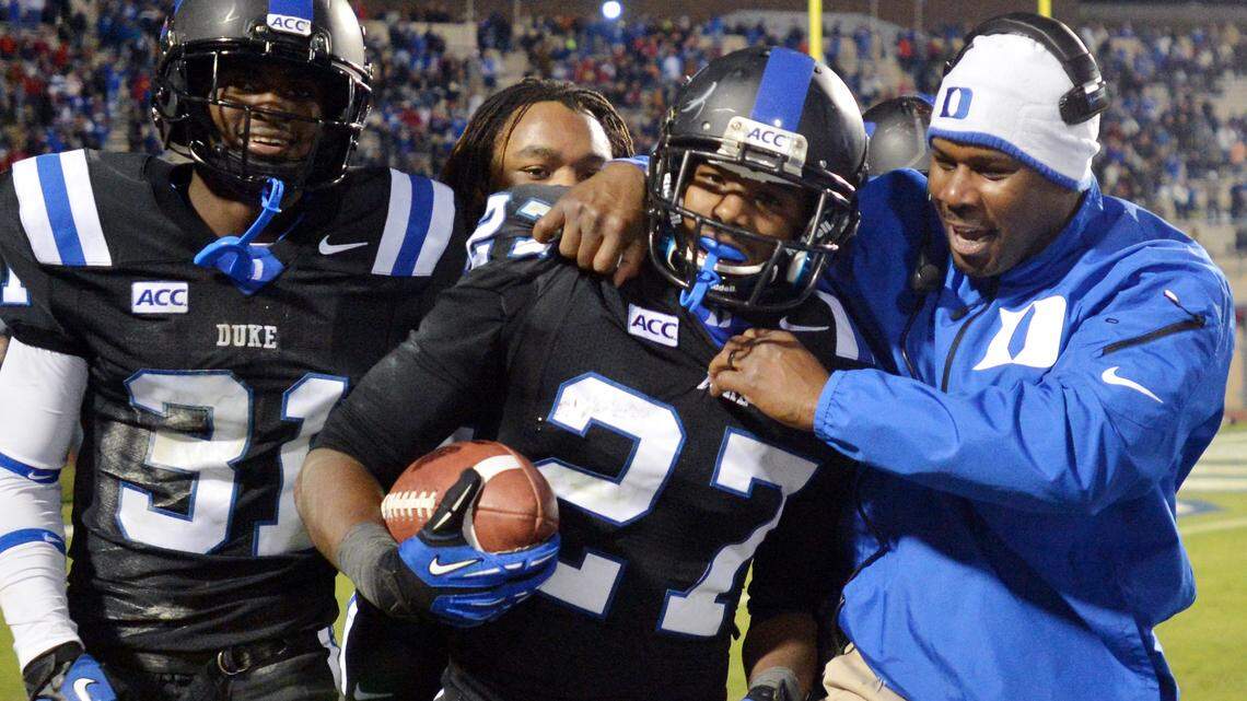 Duke assistant coach Derek Jones hugs cornerback DeVon Edwards (27) after he scores his third touchdown on a fourth quarter interception against N.C. State. Duke beat N.C. State 38-20 at Wallace Wade Stadium Saturday Nov.9, 2013.