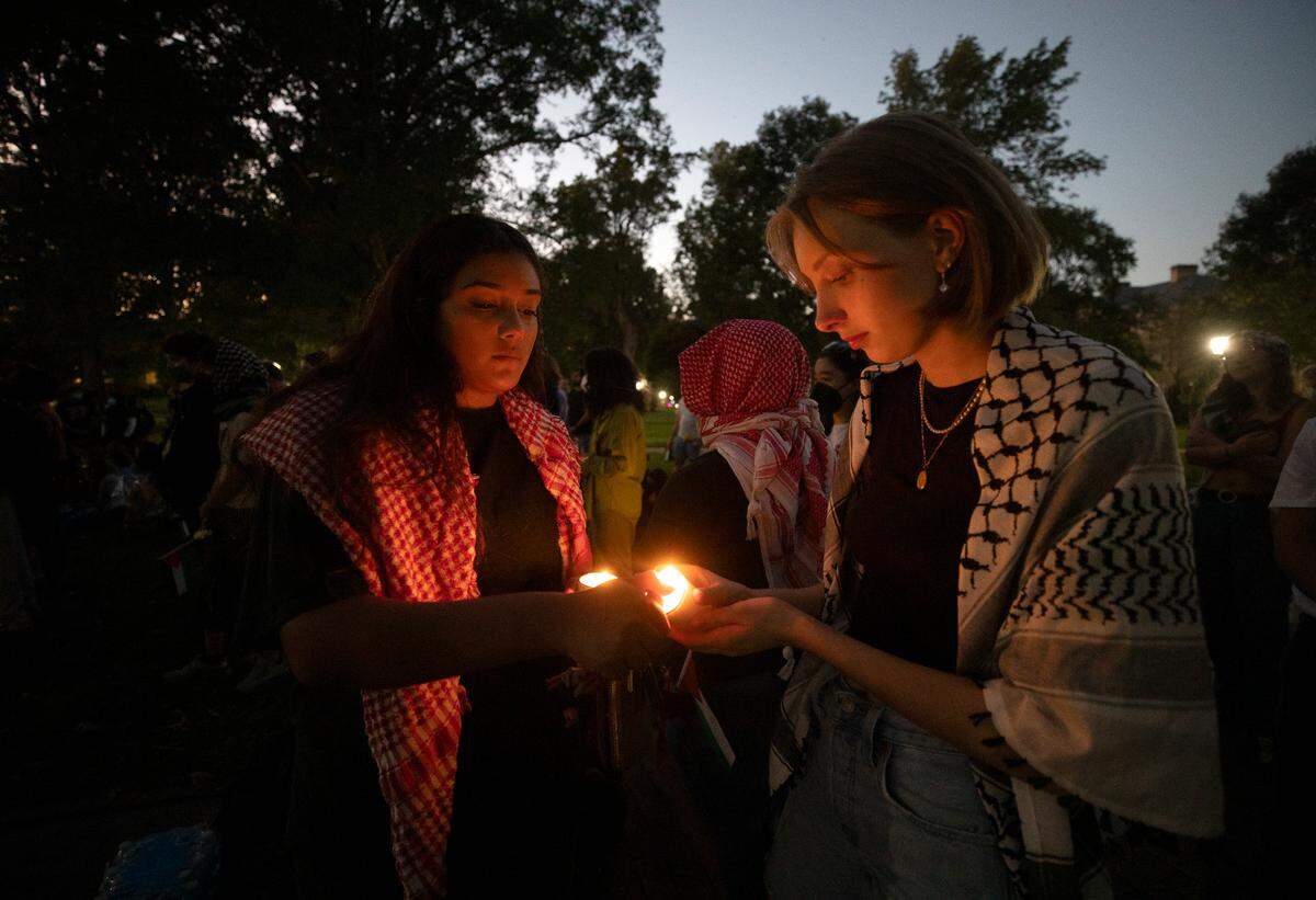 Jannah Said, left, helps to light a candle during a vigil held by the UNC chapter of Students for Justice in Palestine on Monday, Oct. 7, 2024, in Chapel Hill, N.C. The vigil was intended to honor those who have been killed during Israel’s counter-campaign against Hamas in the past year.