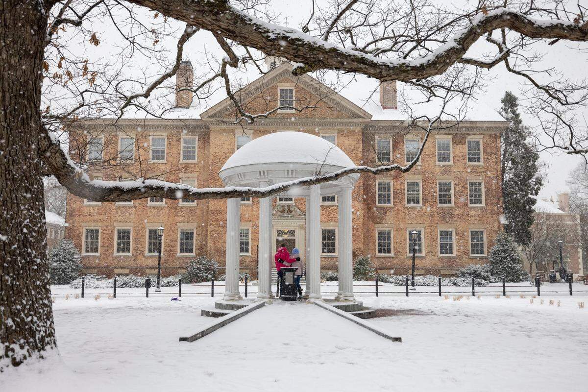 University of North Carolina students Ashton Jarman and Grace Glasgow pose for a photograph at the snow covered Old Well on campus as a winter storm moves through the area on Wednesday, February 19, 2025 in Chapel Hill, N.C.