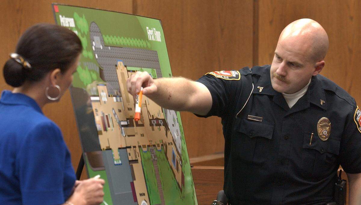 Durham police Cpl. Scott Kershaw describes where he walked in a house the night Kathleen Peterson was killed in December 2001 during testimony Thursday July 10, 2003, in Michael Peterson’s murder trial. Peterson is on trial for the murder of his wife. At left is Assistant District Attorney Freda Black.