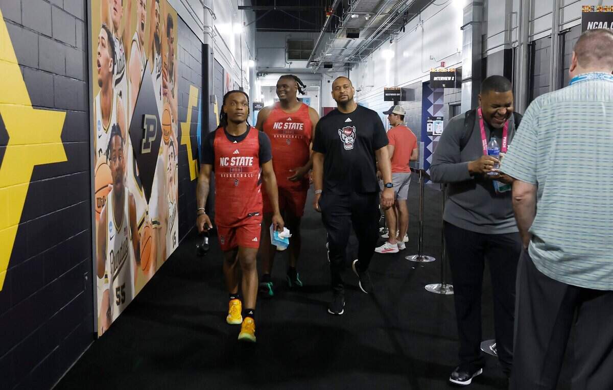 N.C. State’s DJ Horne, left, DJ Burns Jr. and assistant coach Levi Watkins walk past a Purdue poster as they head to the Wolfpack locker room before an availability at State Farm Stadium in Glendale, Ariz. Thursday, April 4, 2024. The Wolfpack will face Purdue in the Final Four on Saturday.