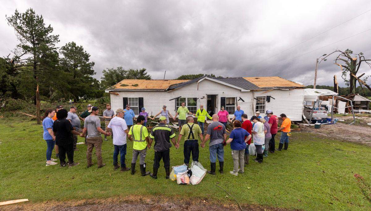 Volunteers with Bridge Church Kentucky Mission Team pray outside of a home that was damaged by a tornado that spun out of Tropical Storm Debby early Thursday Aug. 8, 2024 in Wilson County. Multiple homes and a middle school were heavily damaged by the tornado.