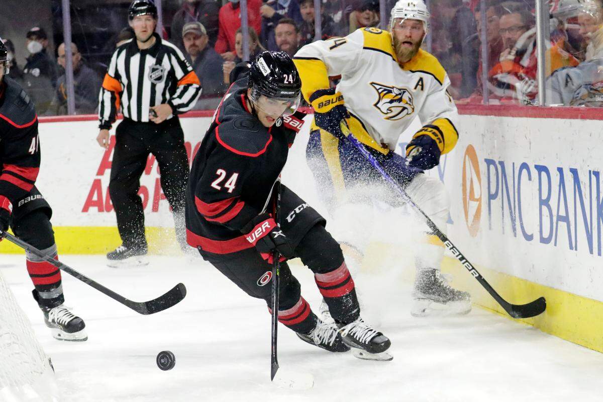 Carolina Hurricanes center Seth Jarvis (24) works the puck against Nashville Predators defenseman Mattias Ekholm (14) during the first period of an NHL hockey game Friday, Feb. 18, 2022, in Raleigh, N.C. (AP Photo/Chris Seward)