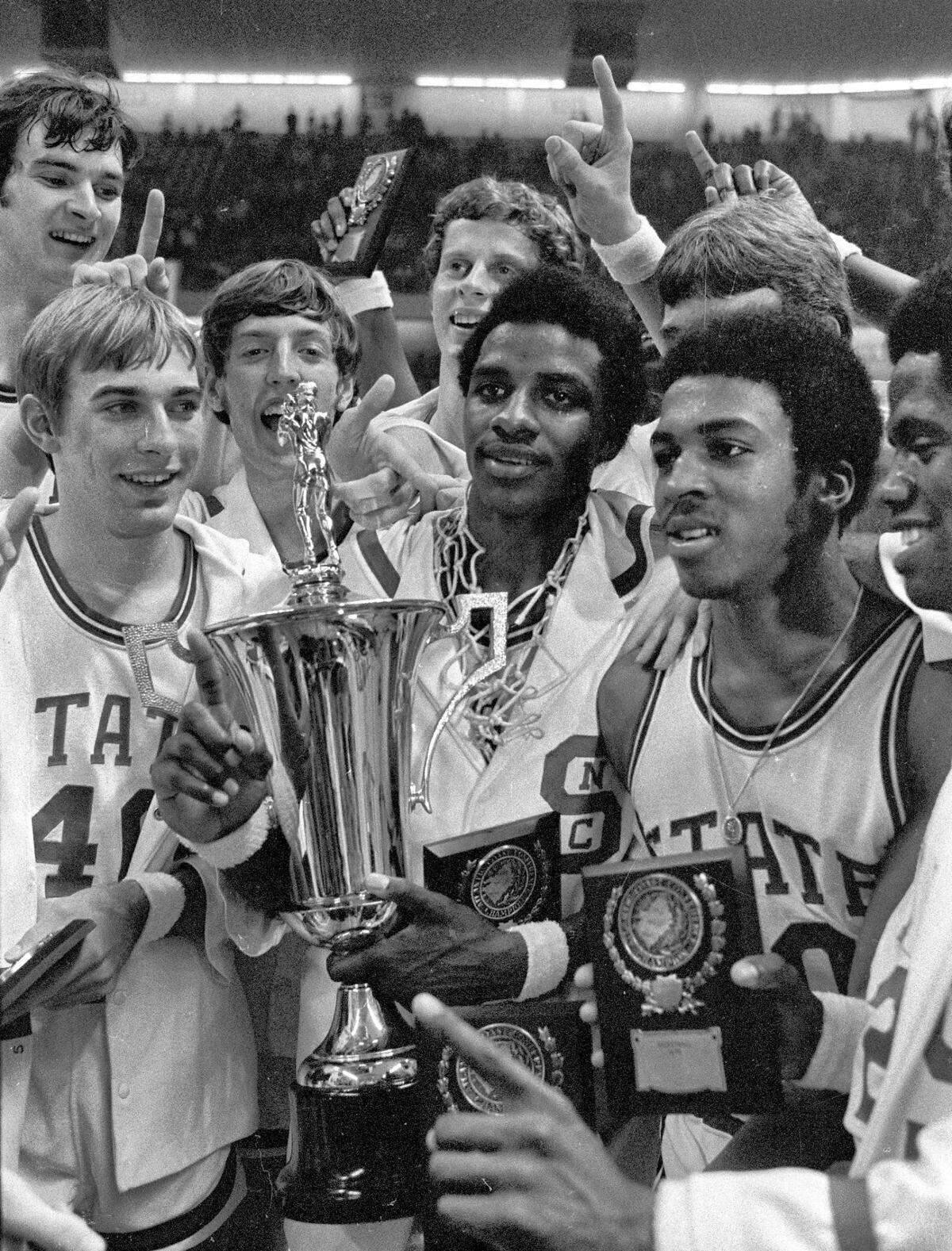 NC State players celebrate with the ACC Tournament championship trophy after their win in 1974.