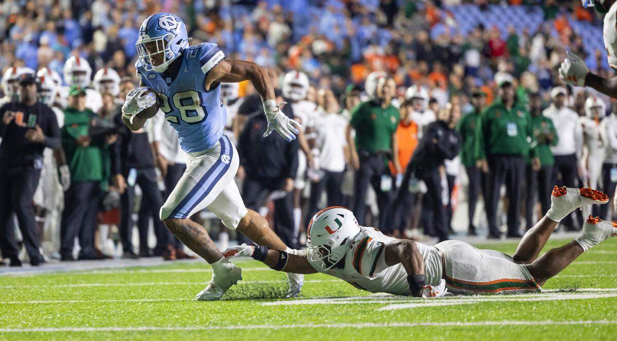 Miami’s Corey Flagg Jr. (11) tries to stop North Carolina running back Omarion Hampton (28) on a nine-yard gain in the fourth quarter on Saturday, October 14, 2023 at Kenan Stadium in Chapel Hill, N.C.