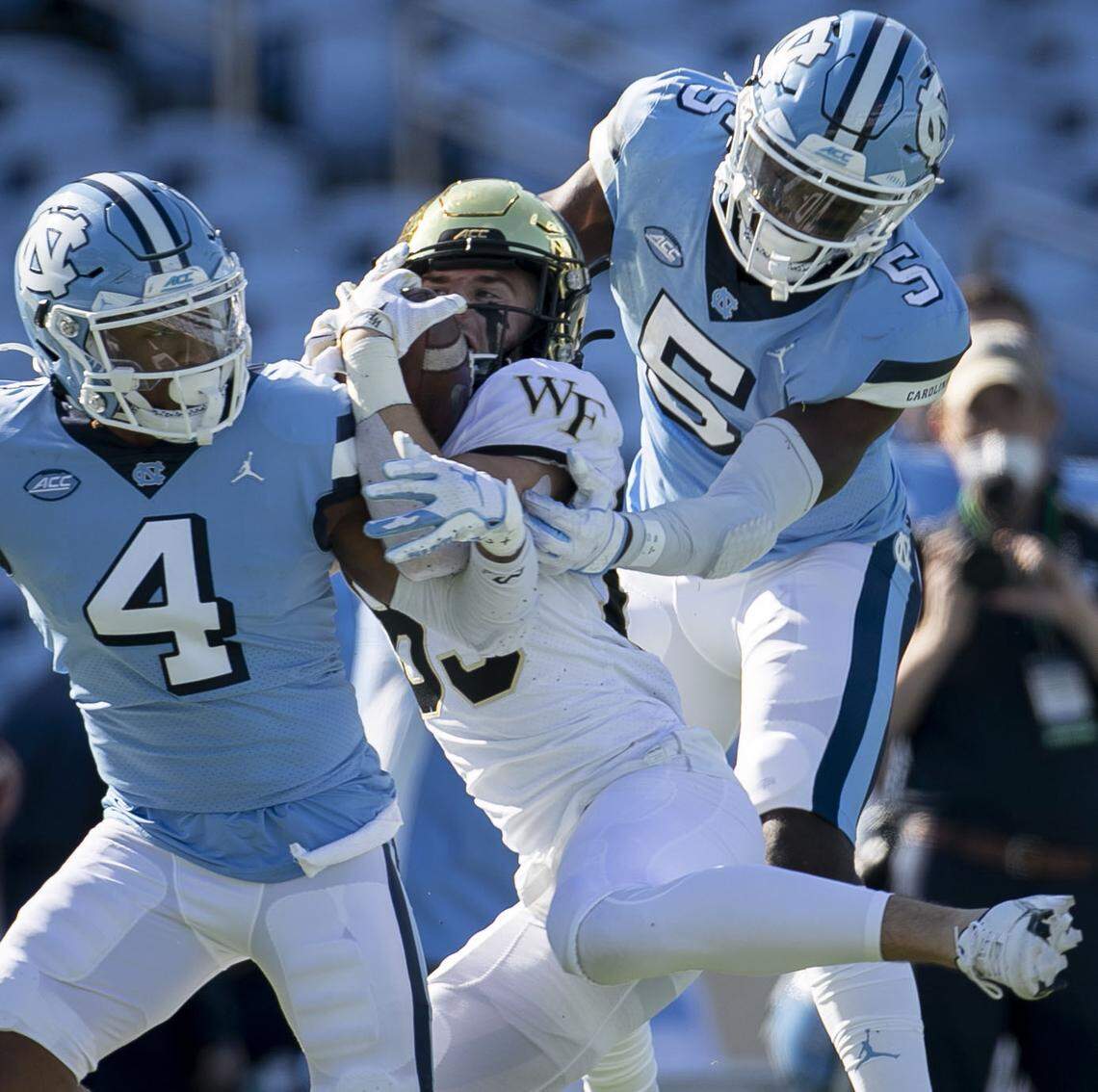 Wake Forest’s Taylor Morin (83) manages to maintain control of a 28-yard pass reception from quarterback Sam Hartman (10) in the second quarter under defensive pressure from North Carolina’s Patrice Rene (5) and Trey Morrison (4) at Kenan Stadium on Saturday, November 14, 2020 in Chapel Hill, N.C.