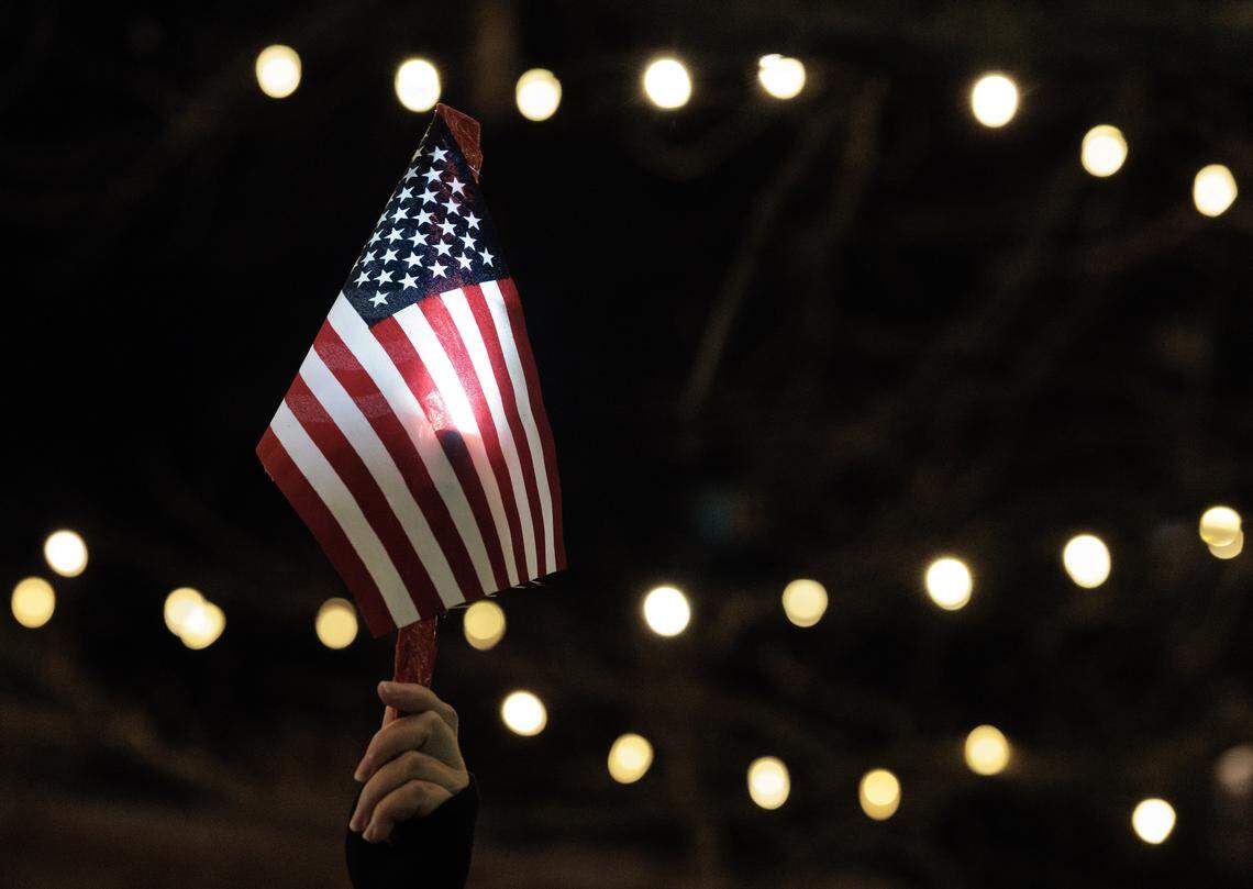 A person holds an American flag during a protest in downtown Durham on Thursday, Jan. 8, 2026, held in response to Wednesday’s fatal shooting of Renee Nicole Good by a federal immigration agent in Minneapolis.