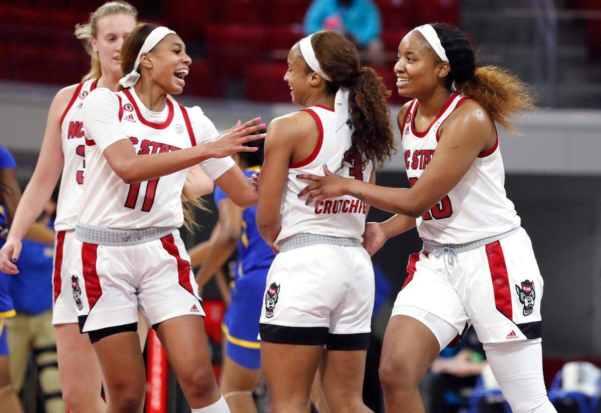 N.C. State’s Jakia Brown-Turner (11), left, and Kayla Jones (25) celebrate with Kai Crutchfield (3) during the second half of N.C. State’s 83-53 victory over Pittsburgh at Reynolds Coliseum in Raleigh, N.C., Thursday, February 25, 2021.