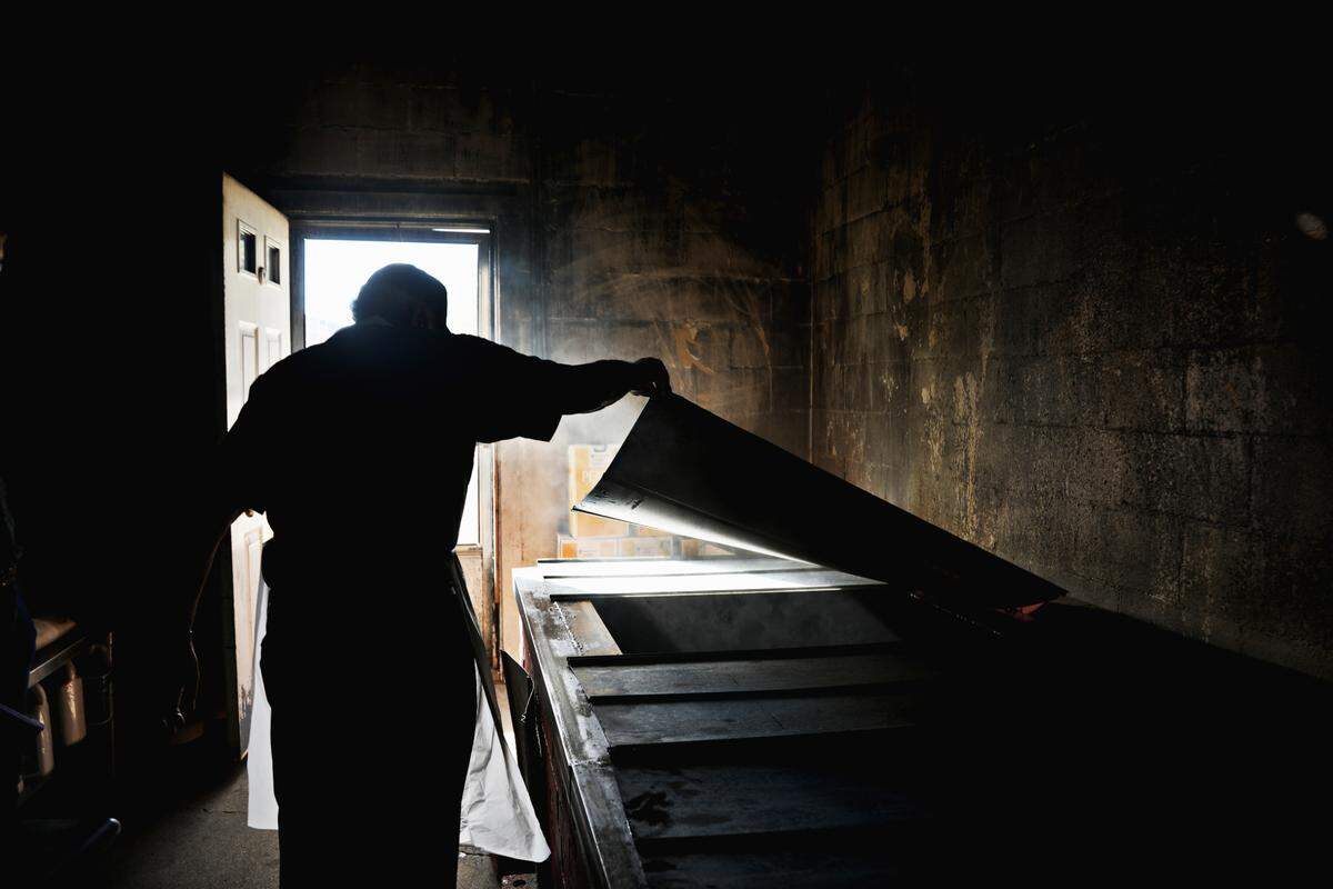 Steve Grady checks on the coals in the smokehouse Oct. 30, 2020, at Grady’s Barbecue in Dudley, NC. The Gradys cook whole-hog barbecue the old-fashioned way, smoked over hickory and oak in a pit.
