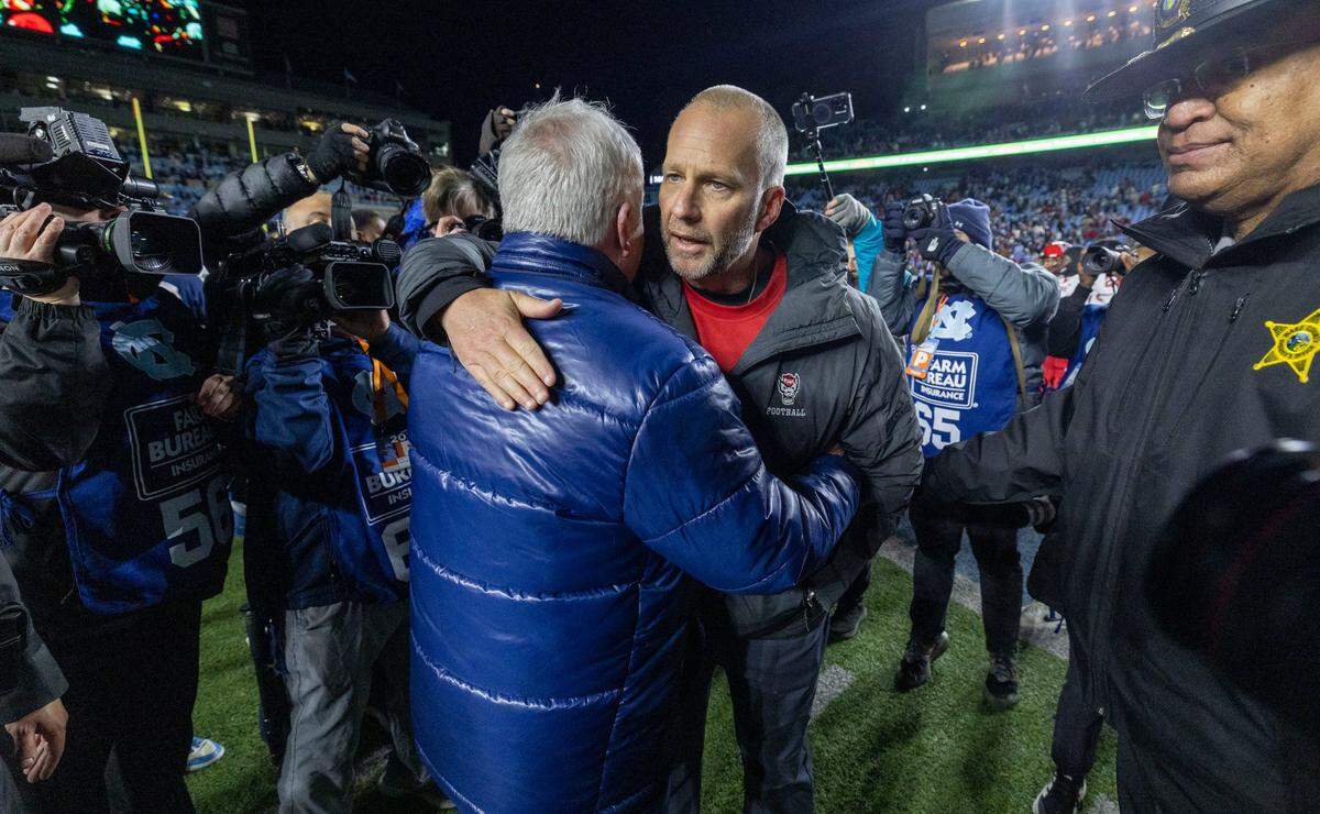 North Carolina coach Mack Brown congratulates N.C. State coach Dave Doeren following the Wolfpack’s 35-30 victory on Saturday, November 30, 2024 at Kenan Stadium in Chapel Hill, N.C.