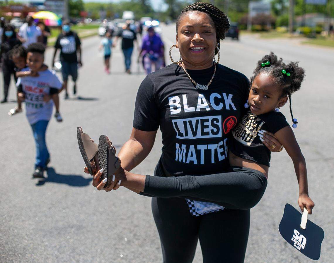 Whitley Johnson carries her daughter Jmiya Wyche after a long march with demonstrators on Eringhuas Street on Saturday, May 1, 2021 in Elizabeth City, N.C. This is the eleventh day demonstrators have gathered in Elizabeth City following the death of Andrew Brown Jr. at the hands of Pasquotank County deputies.
