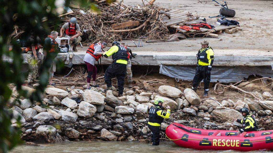 Two people and a dog are escorted to a rescue boat in Chimney Rock, N.C. on Sunday, September 29, 2024.