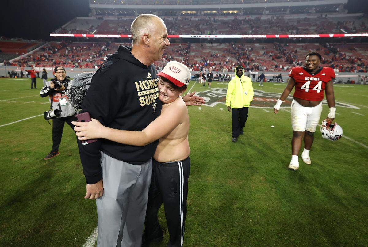 Jackston McDuffie, 12, hugs head coach Dave Doeren after the Wolfpack’s 21-11 victory over Florida State at Carter-Finley Stadium in Raleigh, North Carolina, on Friday, Nov. 21, 2025.