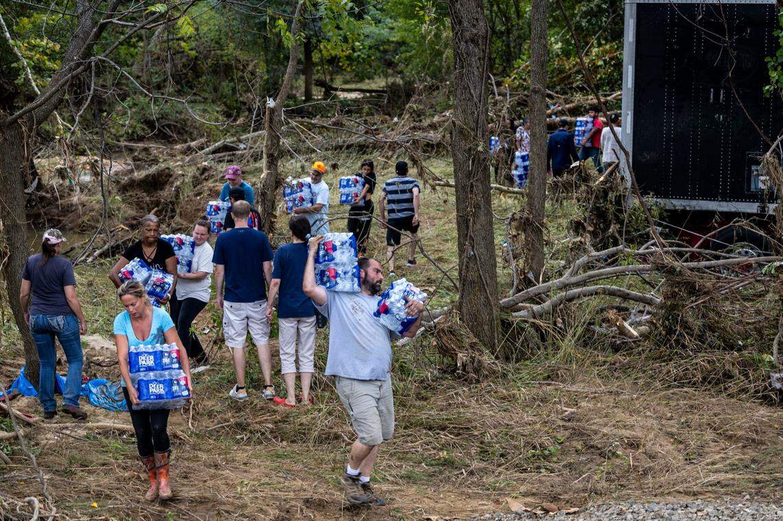 Western North Carolina residents salvage bottled water from a flooded tractor-trailer in Swannanoa on Sunday, Sept. 29, 2024. The remnants of Hurricane Helene caused widespread flooding, downed trees, and power outages in western North Carolina.
