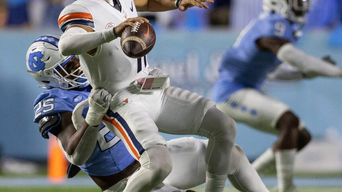 Virginia quarterback Tony Musket (11) is stopped by North Carolina’s Kaimon Rucker (25) in the first quarter on Saturday, October 21, 2023 at Kenan Stadium in Chapel Hill, N.C. Musket was called for intentional grounding.