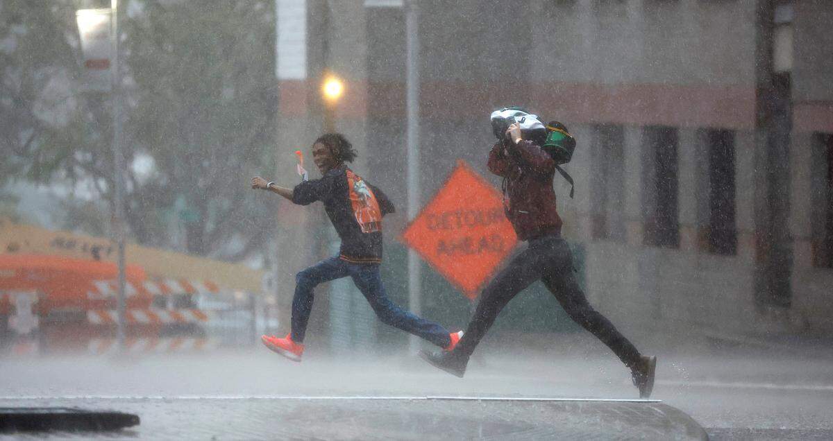 During a downpour, pedestrians run across West Cabarrus St. towards the Raleigh Convention Center in downtown Raleigh Friday, May 27, 2022.