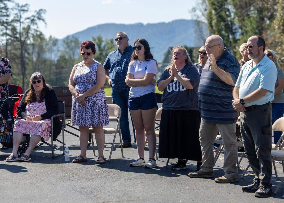 Karen Burnette, right, stands for the closing prayer during services at Salem Free Will Baptist Church on Sunday, October 6, 2024 in Old Fort, N.C. Still without power more than a week after Hurricane Helene, they gathered outside to sing, read scripture and comfort each other.
