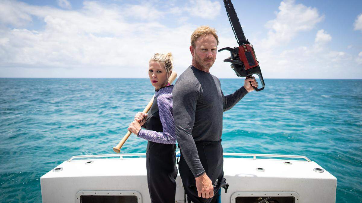 Ian Ziering and Tara Reid pose with their “Sharknado” weapons on a boat in the Shark Week 2021 special “The Real Sharknado”