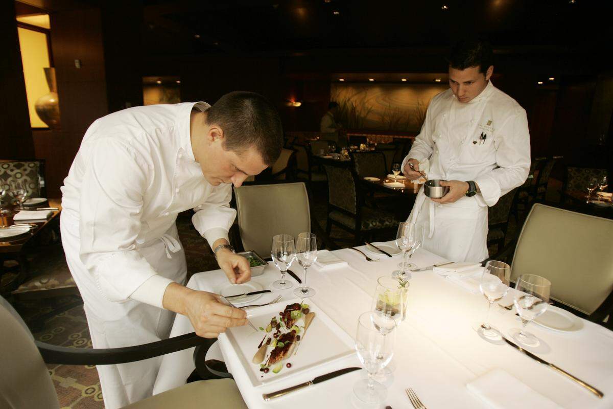 Scott Crawford, the executive chef at Herons, left, and sous chef, Jay Beaver, right, add finishing touches as they plate an entree to be photographed in the dining room.