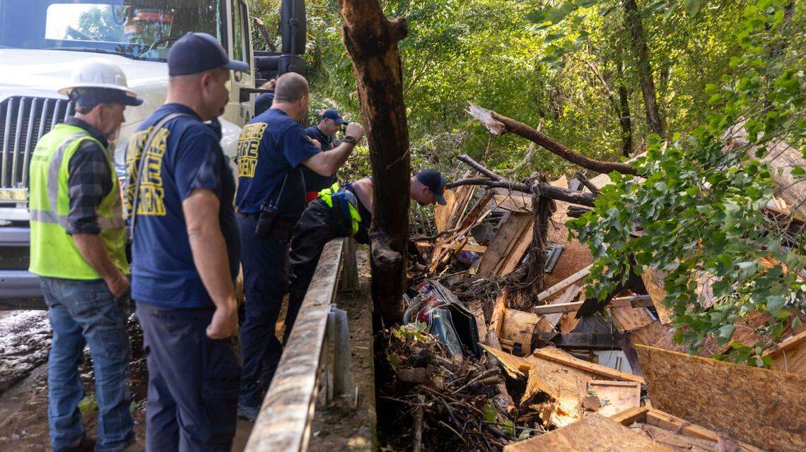 Waynesville firefighters search a car that was pinned by debris under a bridge on Richland Creek in Waynesville on Friday, Sept. 27, 2024 as the remnants of Hurricane Helene caused flooding, downed trees, and power outages in western North Carolina.