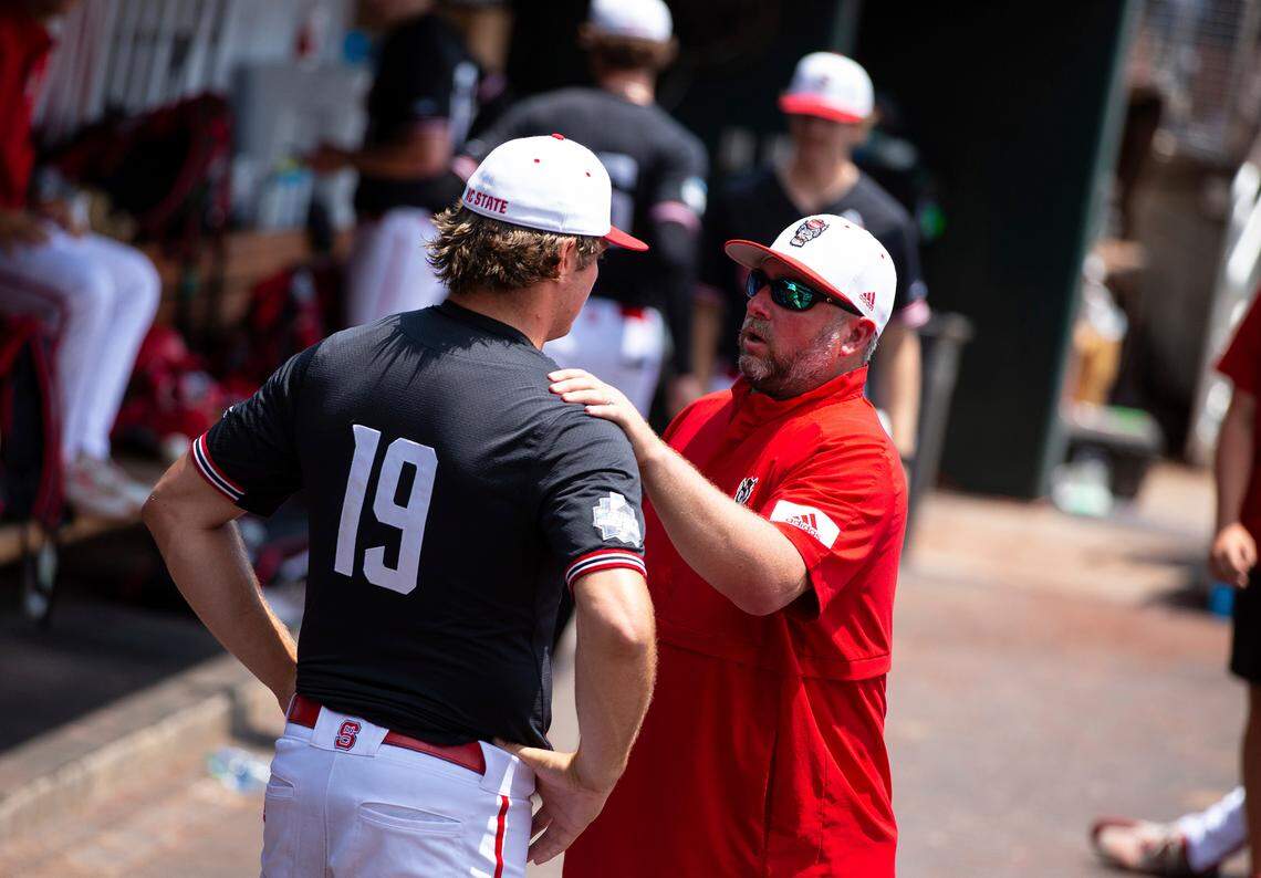 North Carolina State pitching coach Clint Chrysler, right, speaks with right handed pitcher Dalton Feeney (19) in the dugout during a delay due to health and safety protocols before their baseball game against Vanderbilt in the College World Series Friday, June 25, 2021, at TD Ameritrade Park in Omaha.