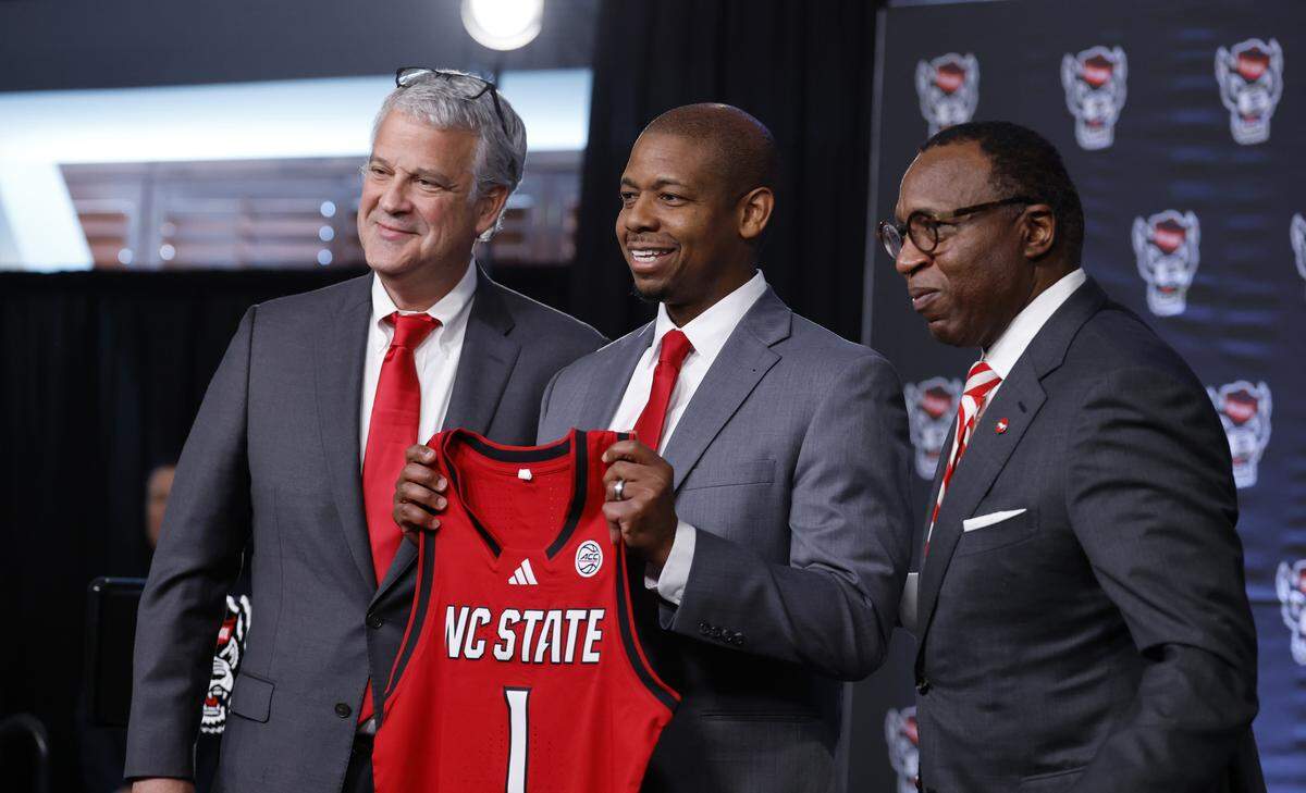 New N.C. State head men’s basketball coach Justin Gainey is flanked by Athletic Director Boo Corrigan and Chancellor Kevin Howell after Gainey was introduced during press conference at the Lenovo Center in Raleigh, N.C.,  Wednesday, April 1, 2026.