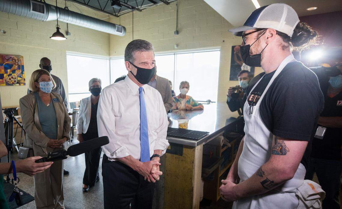 Gov. Roy Cooper speaks with Pizzeria Mercato owner Gabe Barker about vaccines at his Carrboro, N.C. restaurant on Thursday, Aug. 26, 2021.