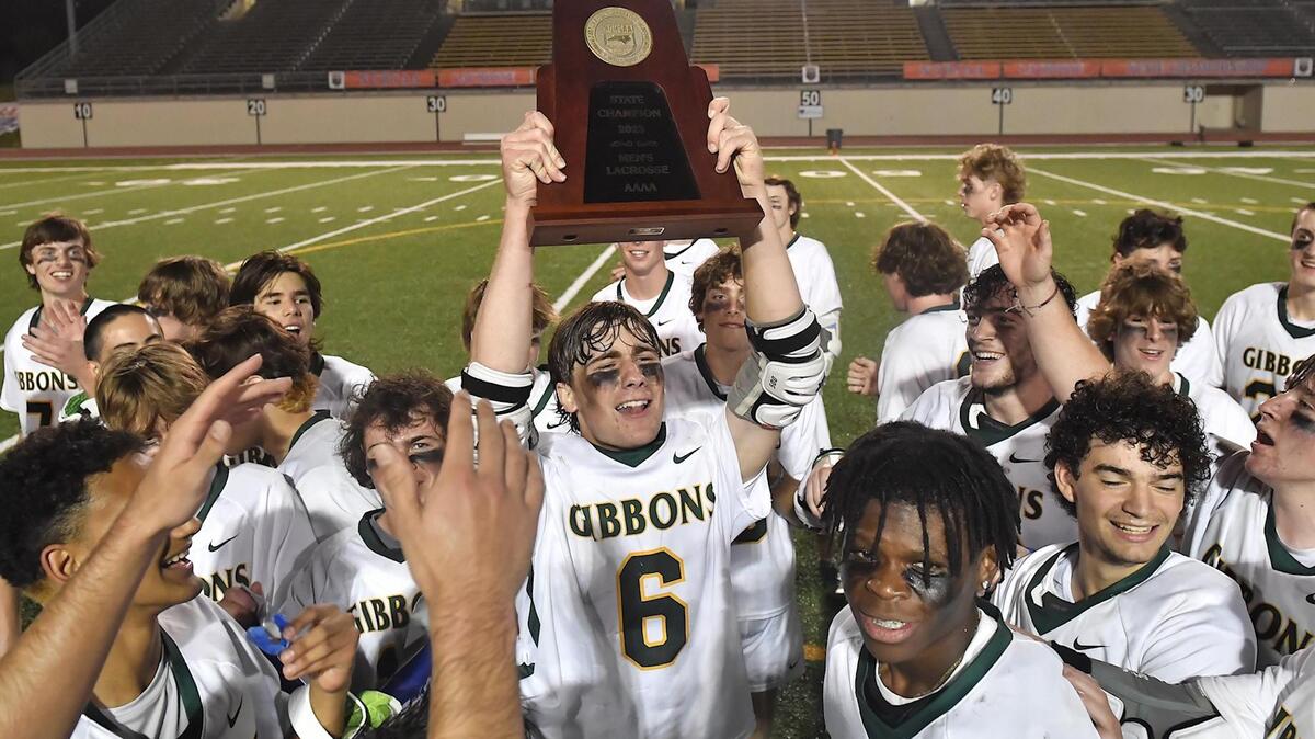 Cardinal Gibbons’ Charlie Carmouche (6) hoists up the 4A Lacrosse Championship trophy and celebrates with teammates after their victory over Charlotte Catholic. The Charlotte Catholic Cougars and the Cardinal Gibbons Crusaders met in the NCHSAA 4A Girls Lacrosse Final in Durham , NC on May 19, 2023.