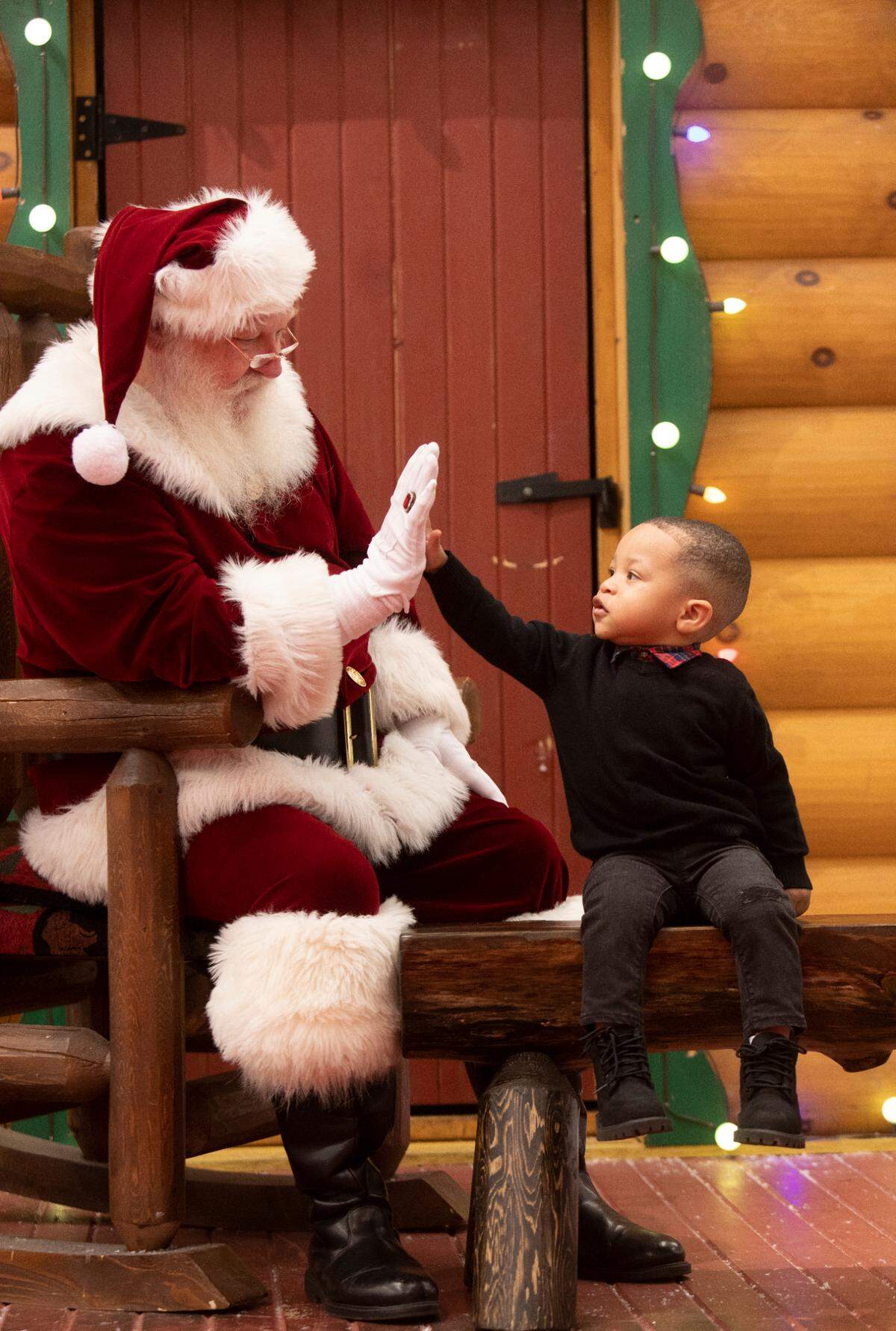Aidyn Crudup, 2, gives Santa a high five during a visit in Santa’s Wonderland at Bass Pro Shop in Cary on Thursday evening, Nov. 11, 2021. Duane Reaugh has professionally worked as Santa for seven years.