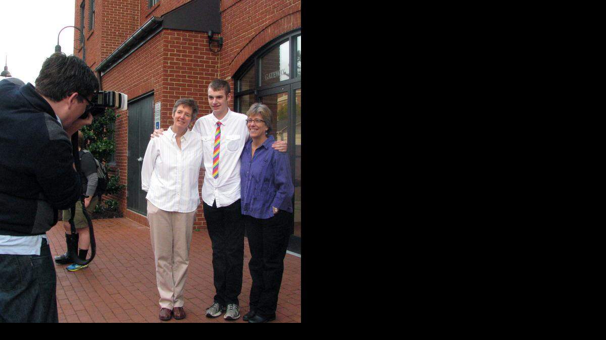Chapel Hill Town Council member Lee Storrow (left) takes a photo of Carrboro Mayor Lydia Lavelle (center), her partner Alicia Stemper (right) and their son Avery while they wait for the Orange County Register of Deeds office to open Monday, Oct. 13, 2014, in Hillsborough, N.C. Lavelle and Stemper were the first same-sex couple to get a marriage license in Orange County. Storrow, an openly gay man who was there to show support for couples getting married, said he’s still looking for Mr. Right.