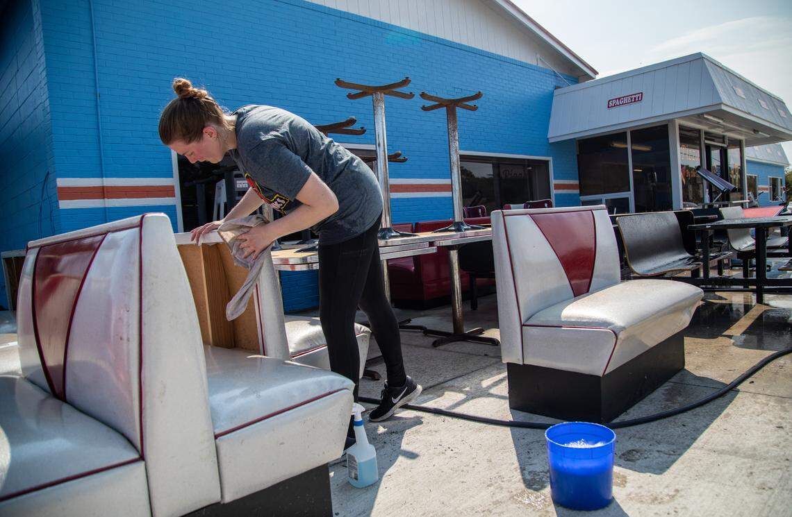 Angelo’s Pizza employee AnnaGrace Gray washes furniture Sunday, Sept. 8, 2019 after the Buxton restaurant flooded during Hurricane Dorian.