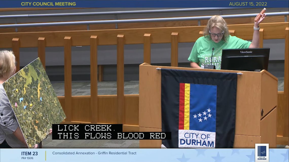 Pam Andrews, right, holds a vial of water she said was collected from Lick Creek at a Aug. 15, 2022 Durham City Council meeting. Andrews was speaking against a residential development proposed along Leesville Road and U.S. 70.