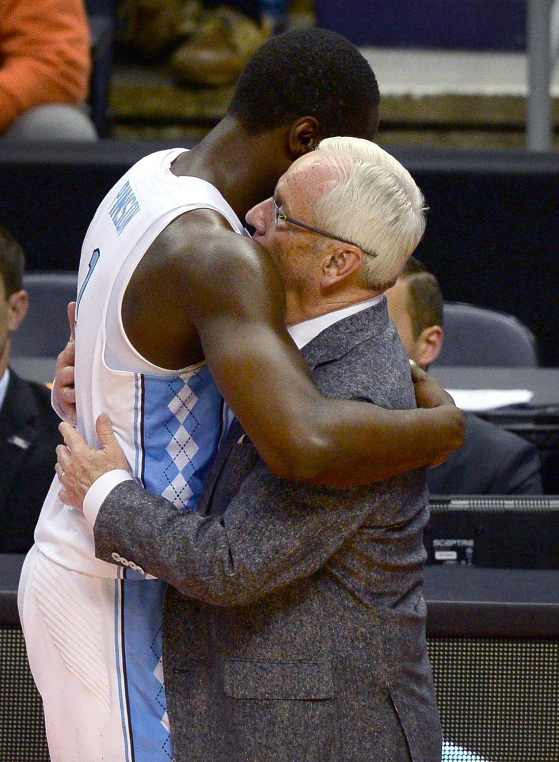 UNC Tar Heels guard Theo Pinson, left, is embraced by head coach Roy Williams as he walks to the team's in the closing seconds of action against Texas A&M during second round action in the NCAA Division I Men's Basketball Tournament at the Spectrum Center in Charlotte, NC on Sunday, March 18, 2018. Texas A&M defeated UNC 86-65.